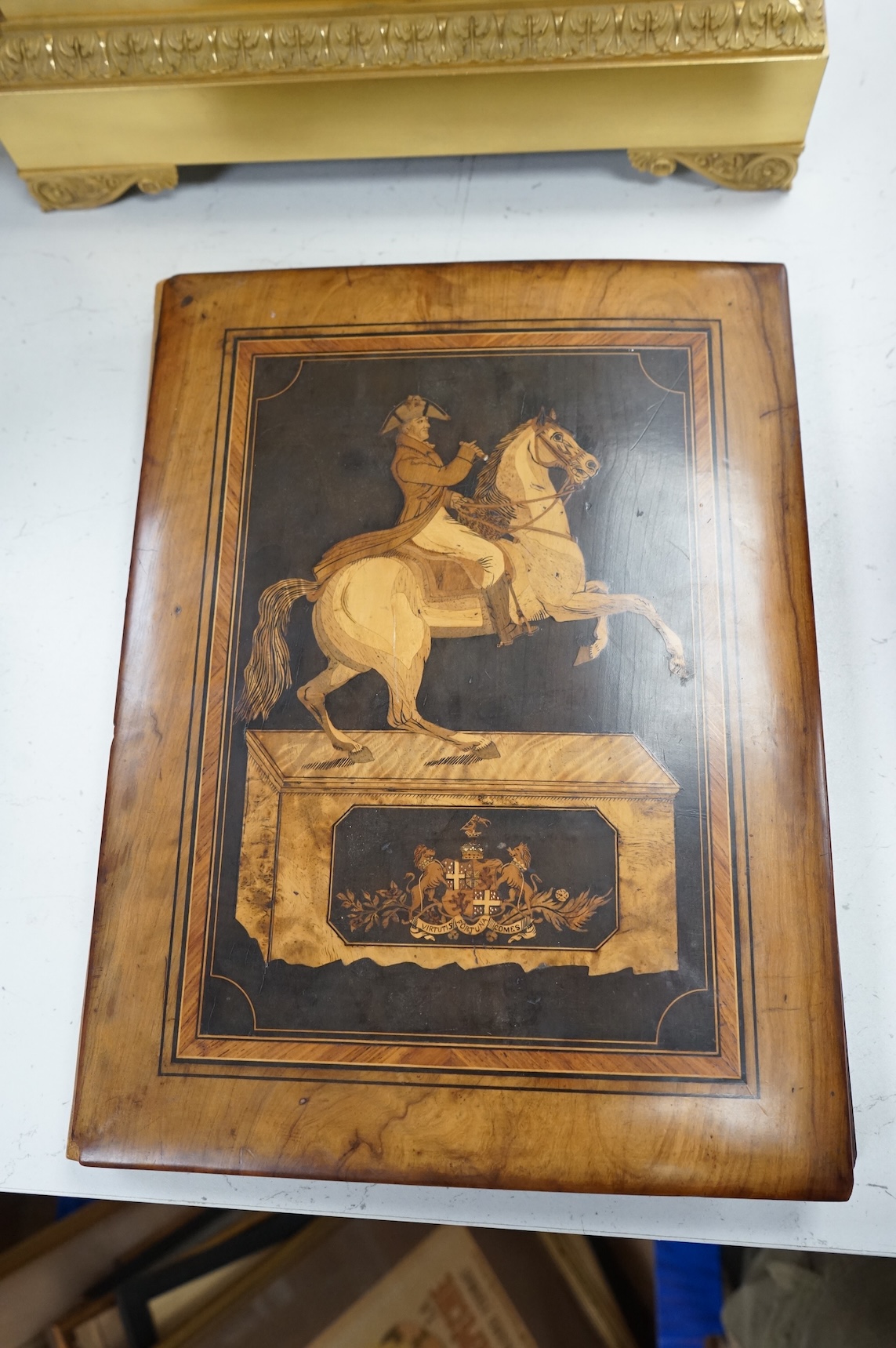 An olive and marquetry desk blotter, Duke of Wellington on horseback and his coat of arms, together with a cloth and gilt book, Army and Navy Drolleries by Captain Seccombe